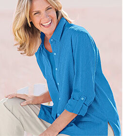 model smiling while wearing a blue shirt and beige pants