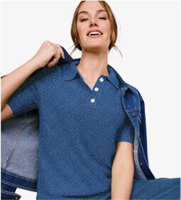 woman wearing blue, collared shirt with jeans jacket on her shoulder