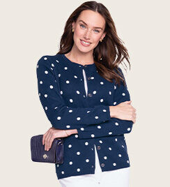 woman with arms crossed wearing navy blue cardigan with large white polkadots