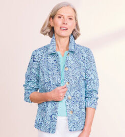 model smiling into the camera wearing a blue and white patterned jacket, teal shirts and white pants