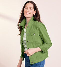 model smiling into the camera wearing a green jacket, and blue pants