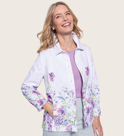 woman smiling into the camera wearing a light lavender jacket with purple floral embroidery