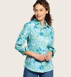 smiling model wearing a light blue and turquoise patterned button-up shirt and blue jeans