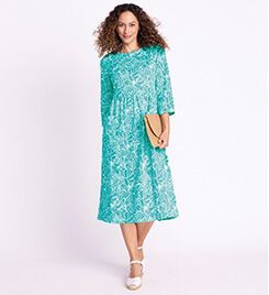 model wearing teal floral dress and white shoes around the waist