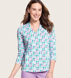 woman smiling into the camera wearing a colorful, checkered shirt