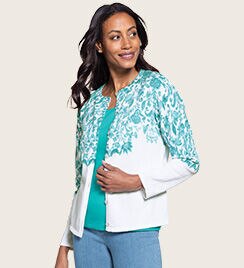 woman facing to the right wearing a white sweater with turquoise trim and light blue pants