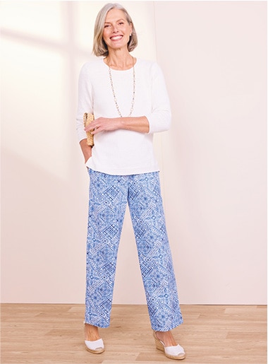 model wearing white top and patterned blue pants with white shoes