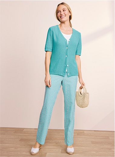 model wearing a top and pants in different green hues over a white tee and with white shoes